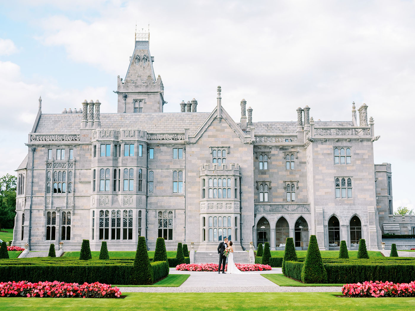 Newly married couple embrace with Adare Manor in the background
