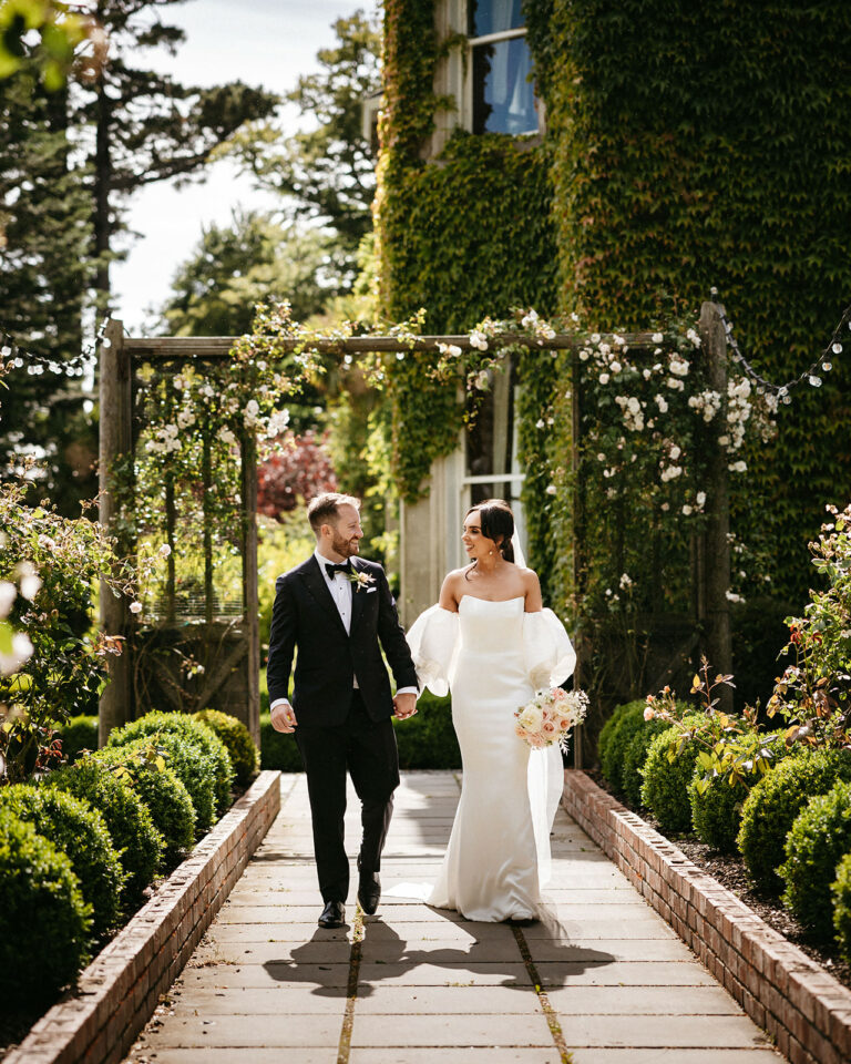 Bride and Groom walking along a path in the gardens of Tinakilly House